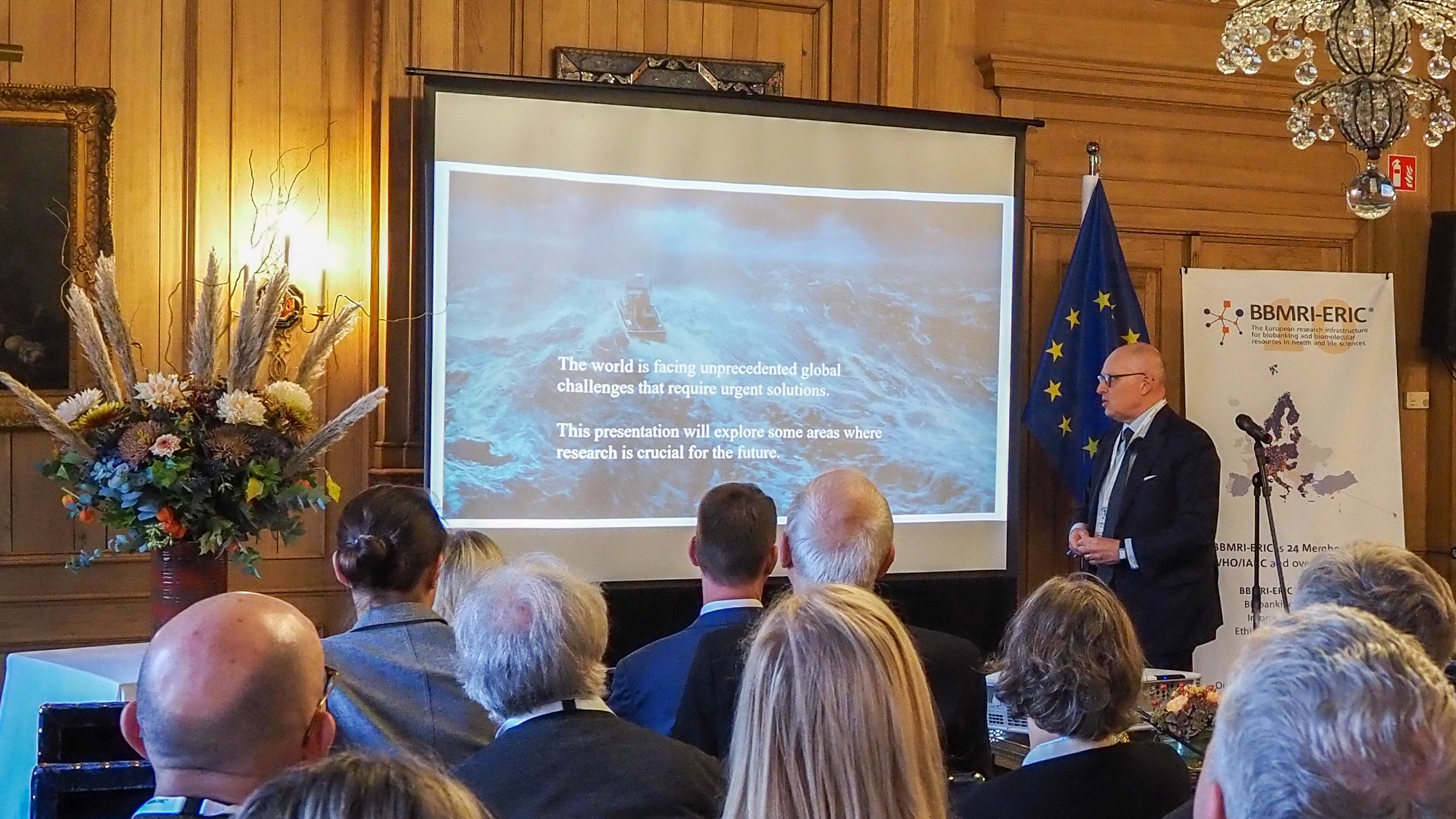 The picture of a man presenting in front of an audience.