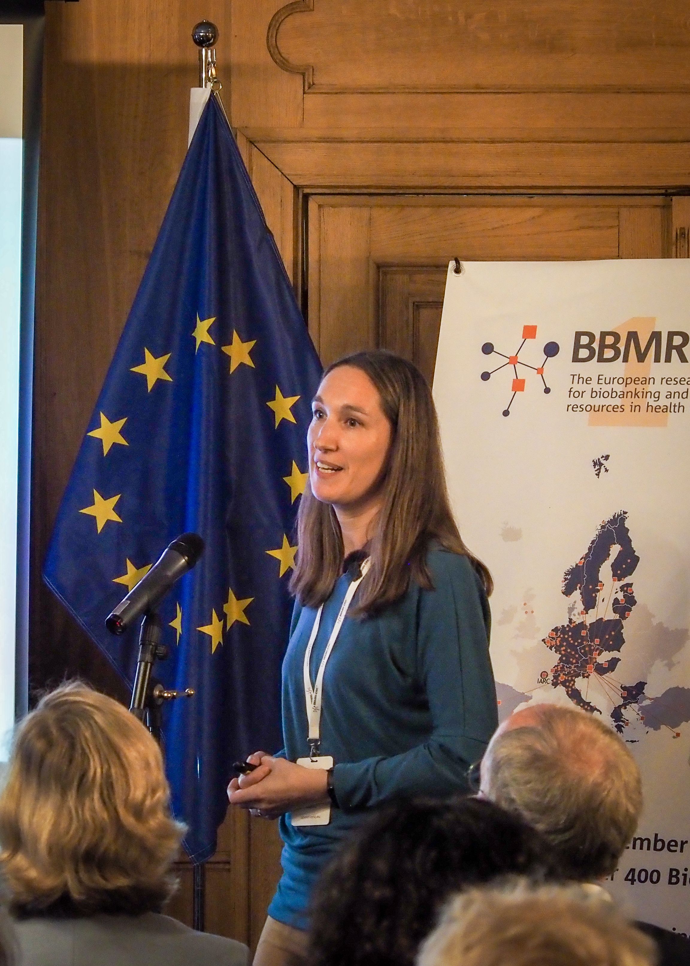 The picture of a white woman with long brown hair presenting to an audience. 
