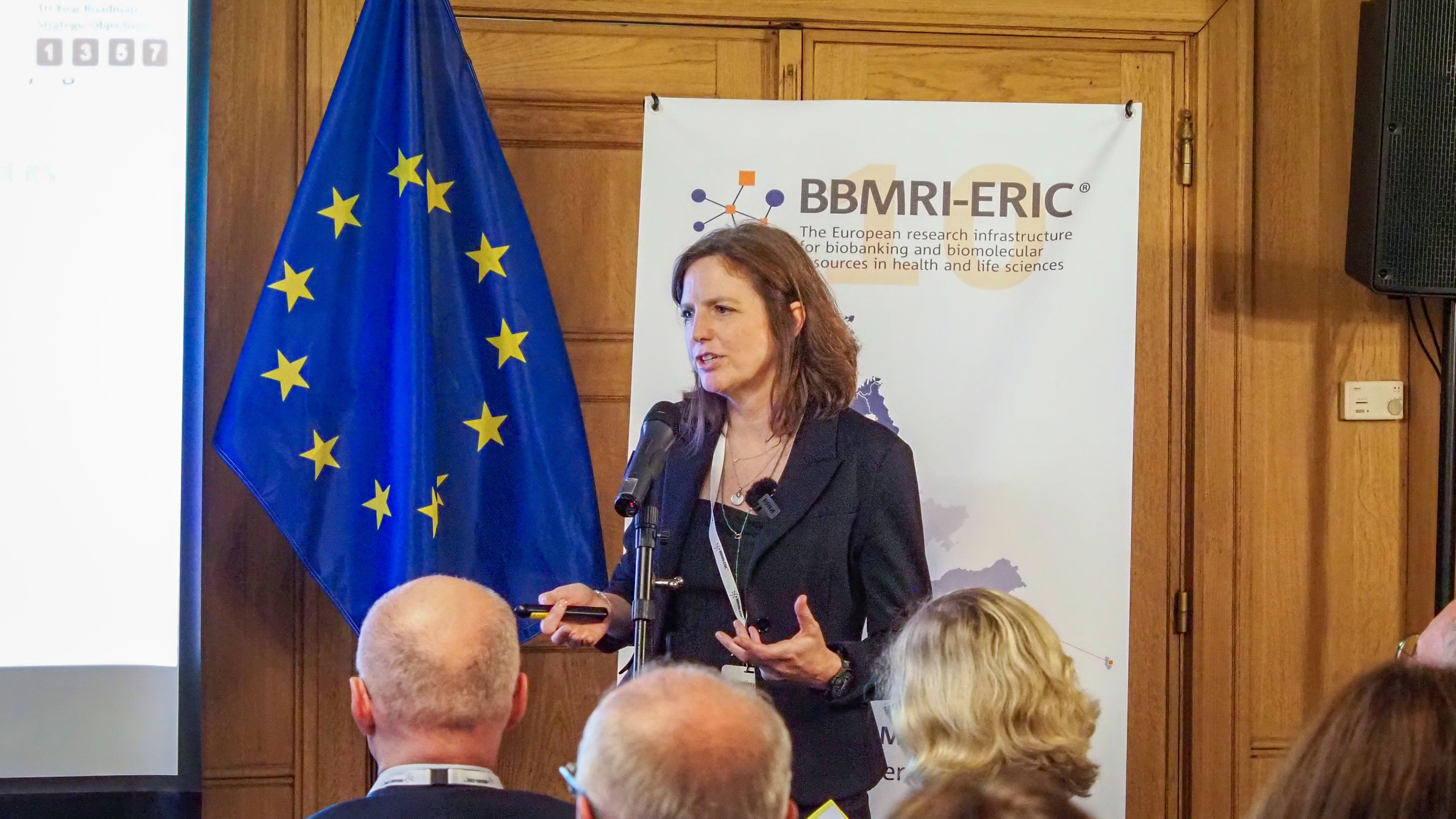 The picture of a white woman with brown hair presenting to an audience. 