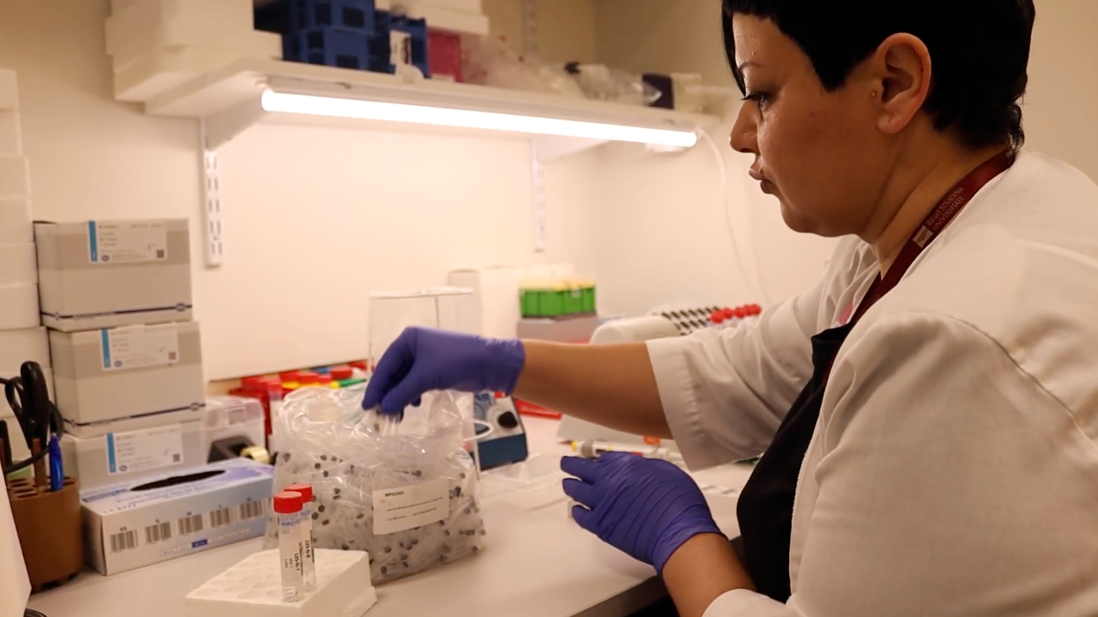 The picture of a woman wearing a white medical gown while filing samples 