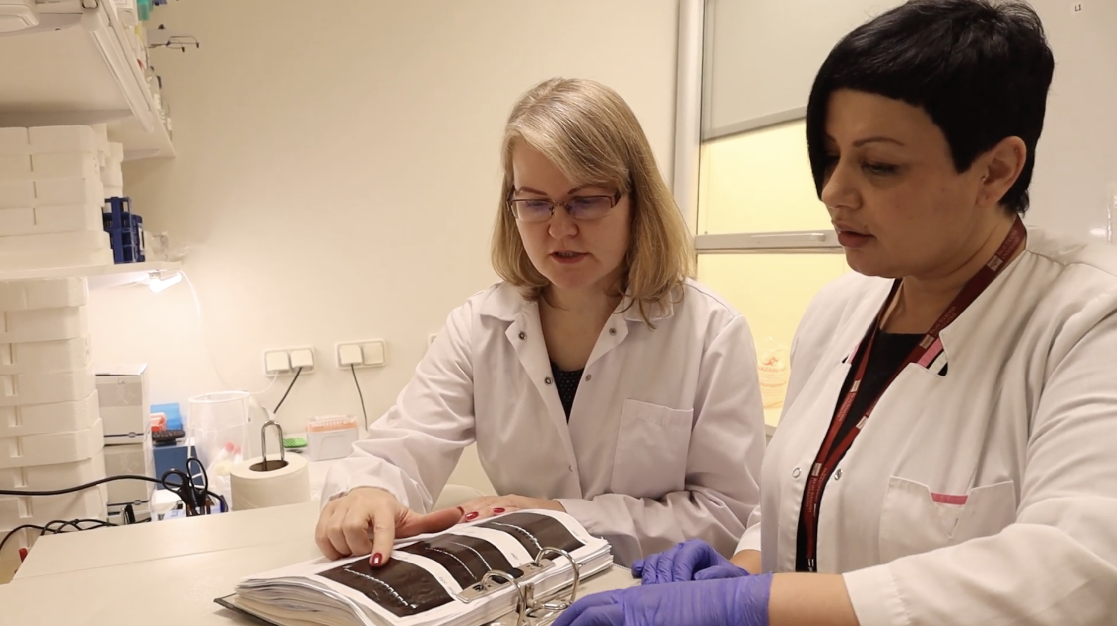 The picture of two women wearing a white medical gown in a laboratory.