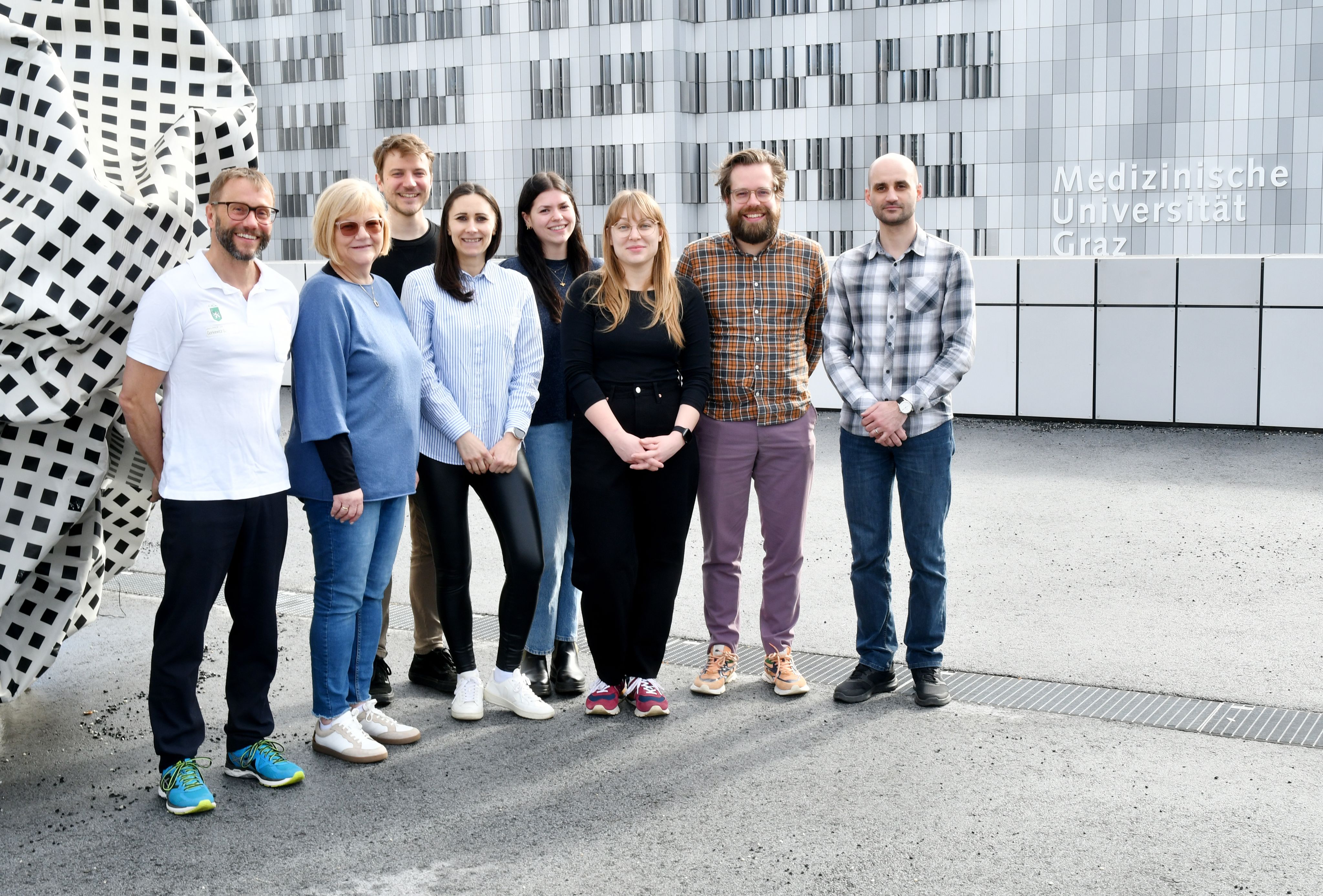 Group of people posing in front of sculpture 