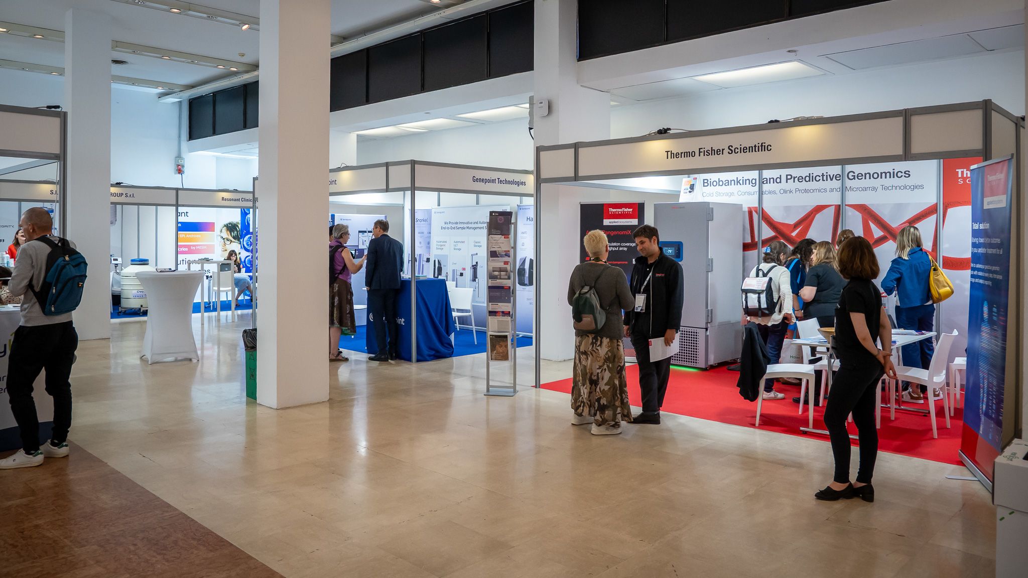 People talking to each other in front of an industry exhibition stand at a conference centre.