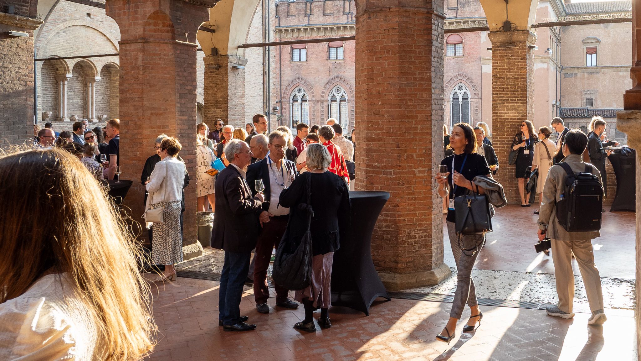 People in festive clothing at a gala networking dinner at a medieval location.