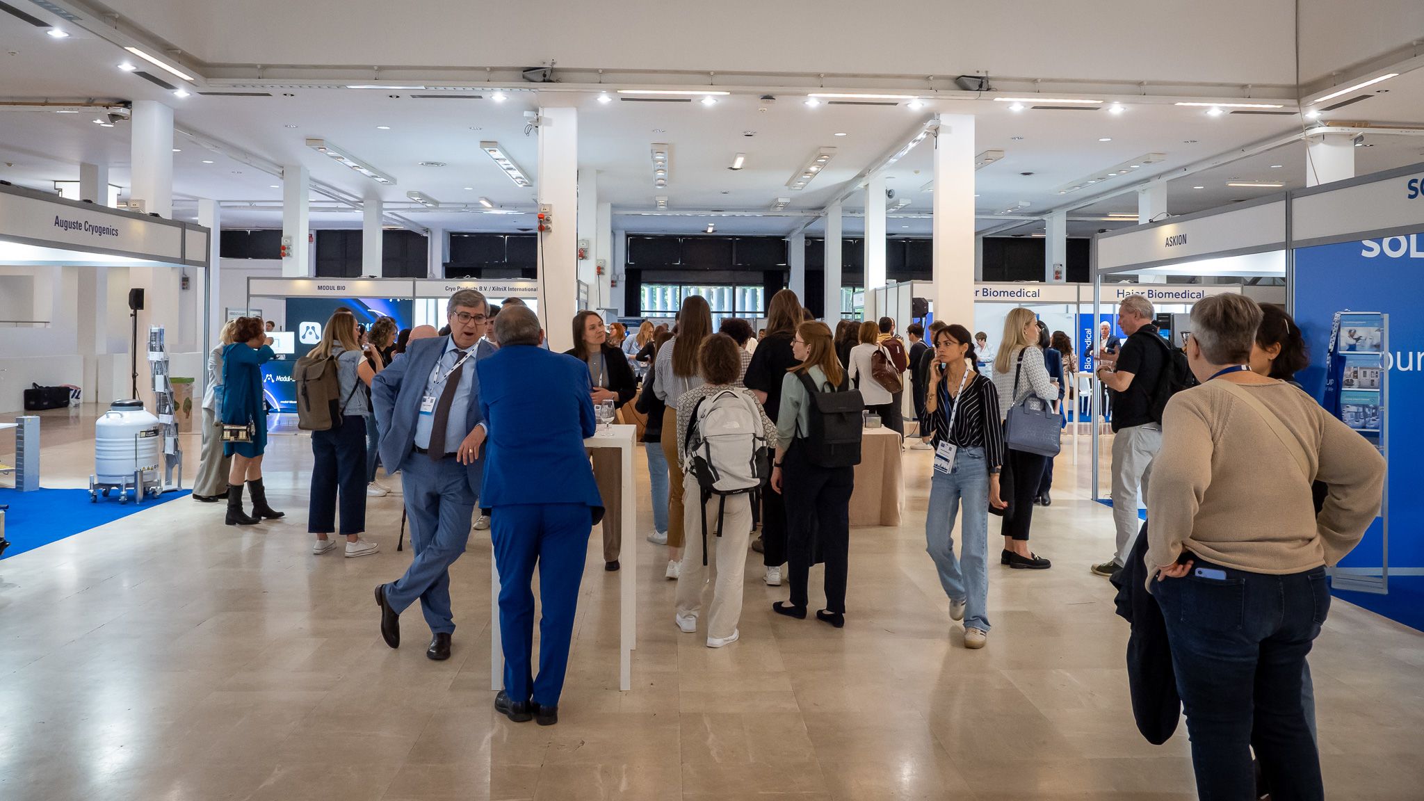 Many people in an exhibition area of a conference centre.