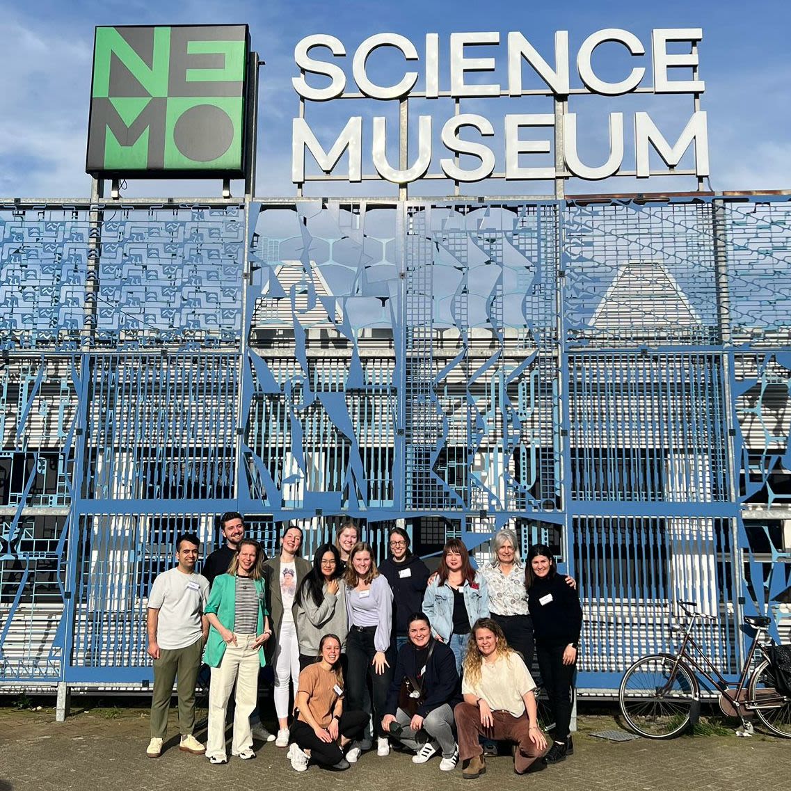 group of adults posing in front of science museum 