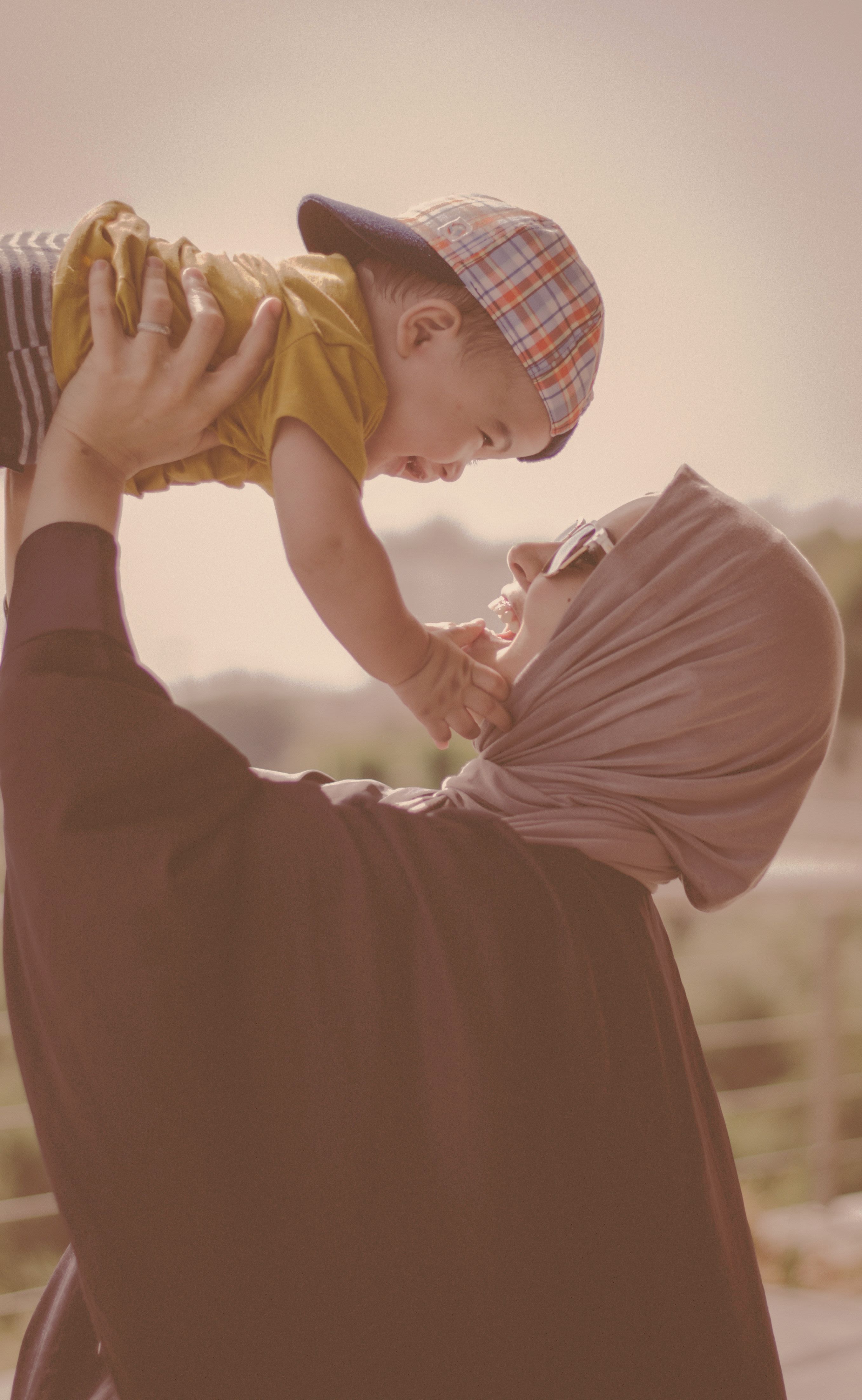 woman holding boy during daytime