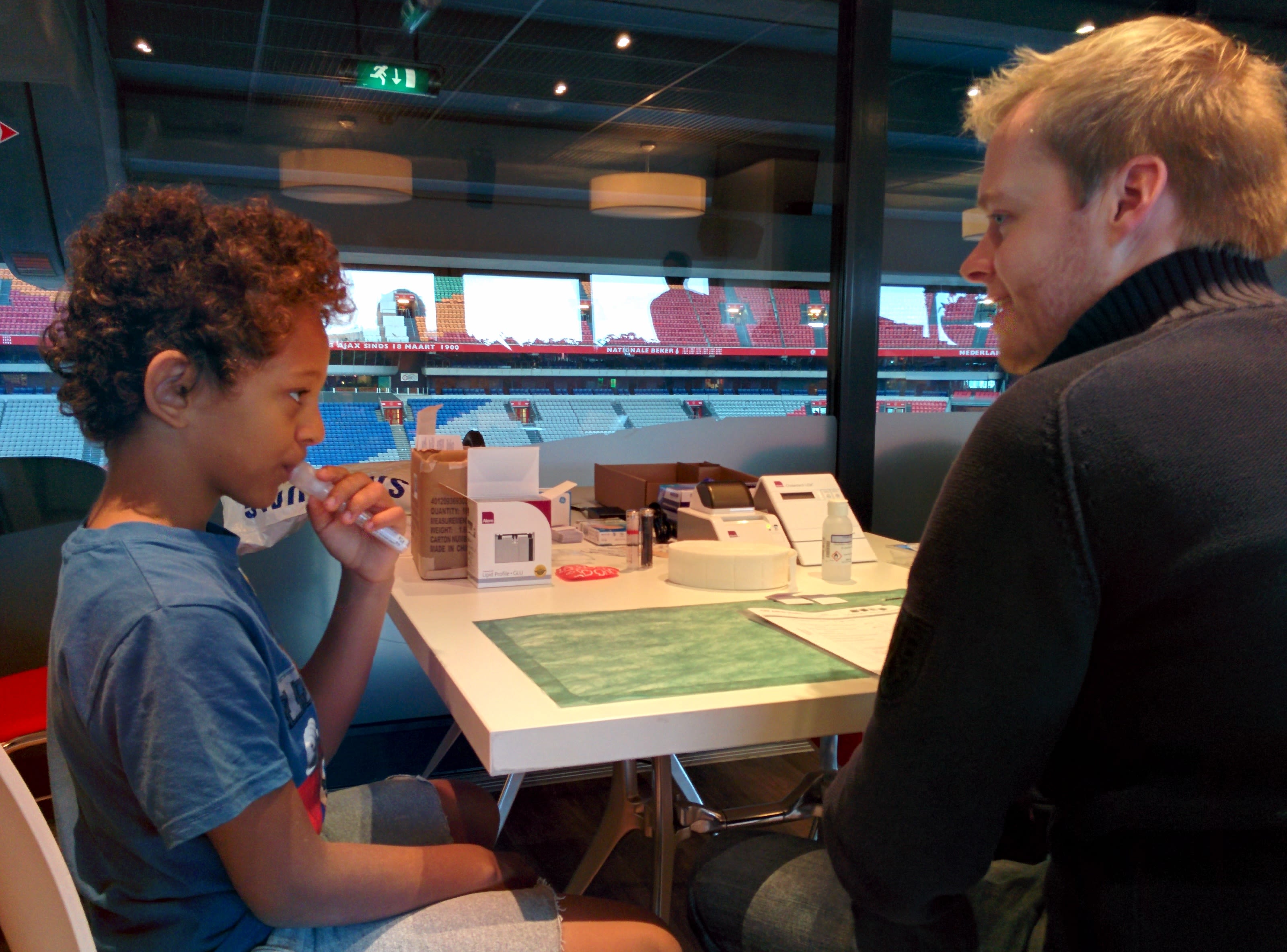 young boy spitting into test tube next to young man